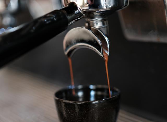 Dobbelt espresso løber fra portafiltret og ned i en mørk keramikkop