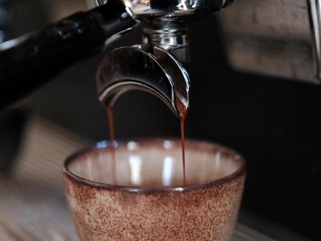 Dobbelt espresso løber fra portafilter og ned i en brunlig keramikkop