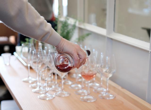 Rosé hældes op i vinglas der står på et bord i et lyst lokale