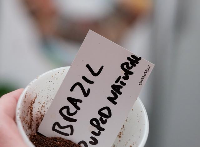 Krus med formalede kaffebønner hvori der ligger et skilt med påskriften Brazil Pulped natural