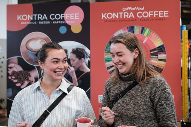 To unge mennesker smiler under en kaffesmagning