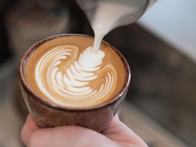 Mælk fra en steamkande rammer overfladen på en espresso og danner latteart