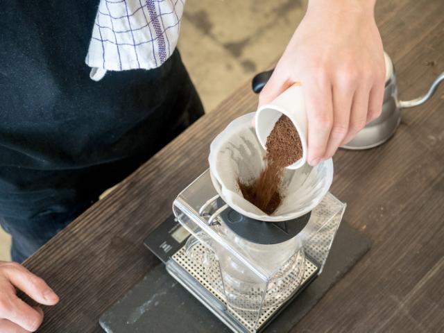 Formalet kaffe hældes i klargjort Hario V60 med skyllet kaffefilter