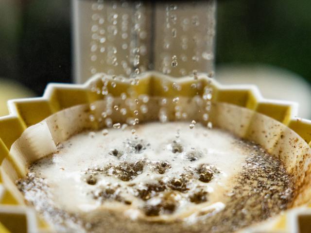 Vand løber ned i en origami kaffetragt med kaffebønner i