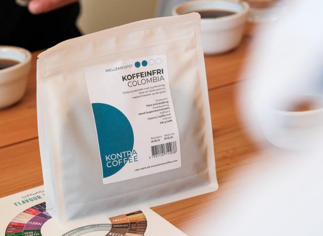 Hvid kaffepose med koffeinfri Colombiansk kaffe står ovenpå et kaffesmagshjul