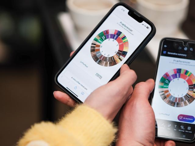 To mobiltelefoner holdes hen mon hinanden mens kaffesmagshjulene på skærmen sammenlignes