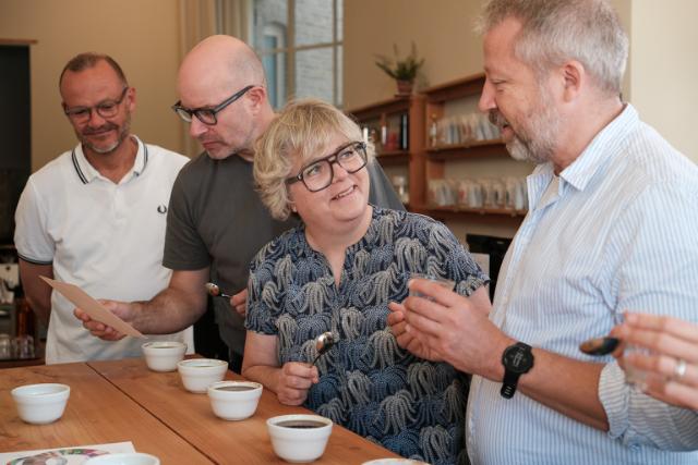 Fire personer på kaffekursus snakker sammnen henover en kaffesmagning