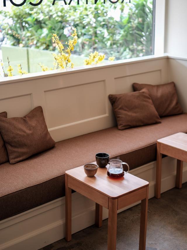 En håndfuld friskristede kaffebønner holdes over en tønde fuld af kaffebønner