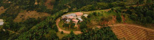 En lille klat huse ligger i et sving på en grusvej i et bjerglandskab