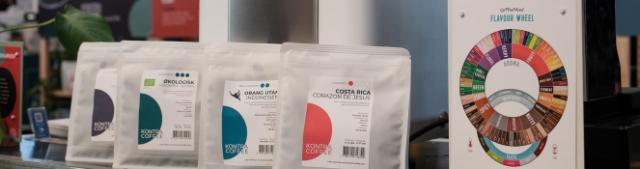 Kaffeposer fra KONTRA COFFEE står på række med et smagehjul for enden af rækken