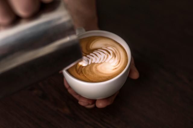 Smuk latteart laves i en kop kaffe