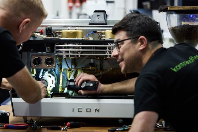 en teknikker holder en lommelygte i forbindelse med reparation af en Icon kaffemaskine