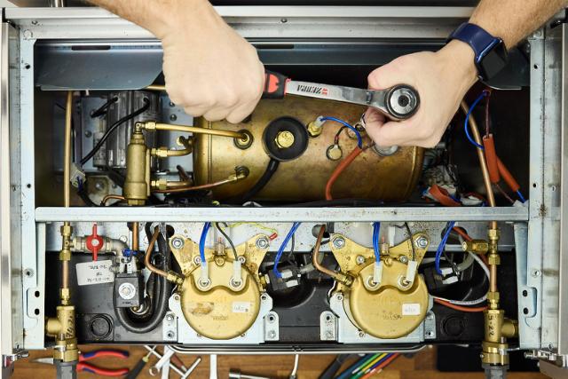 Hænder reparerer på en kaffemaskine set fra oven